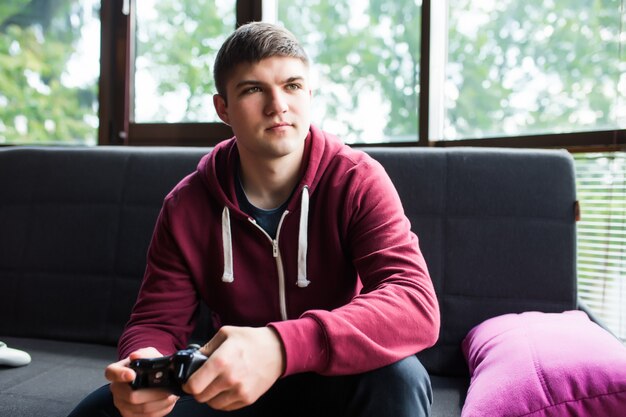 Young happy man laughing and playing video games on weekend