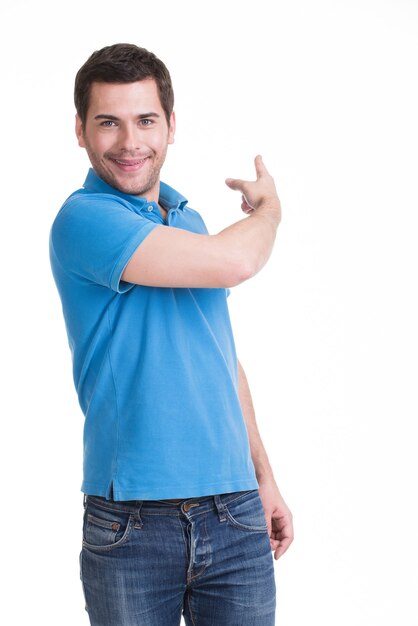 Young happy man shows a finger in the side in casuals - isolated on white.