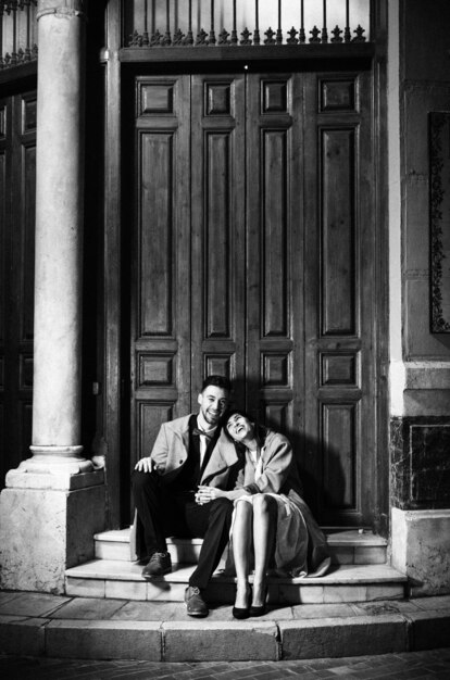 Young happy man and woman sitting near door on street