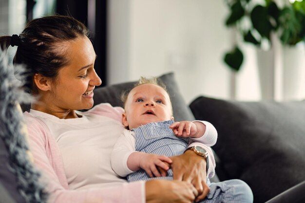 若い幸せな母親と彼女の赤ちゃんは一緒に時間を過ごし、リビングルームでリラックス