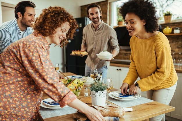 無料写真 家で昼食のために食卓を準備しながら楽しんでいる若い幸せな人々焦点はアフリカ系アメリカ人の女性にあります