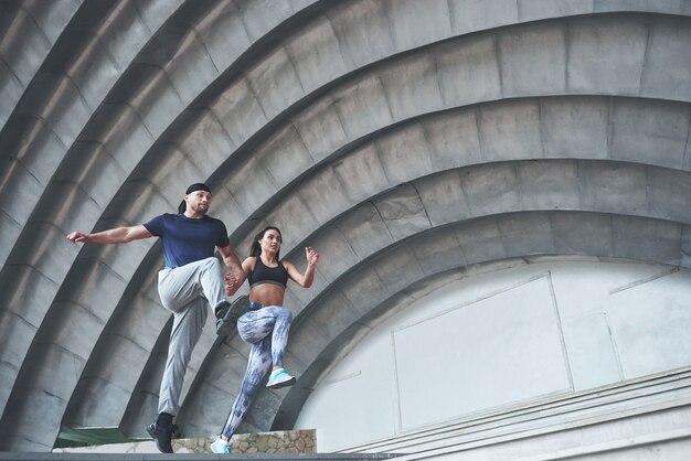 Young happy sports couple in the city street, performing parkour.