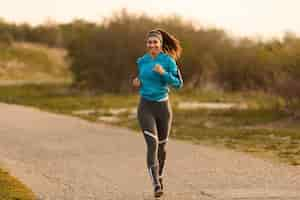 Free photo young happy sportswoman running on the road in the morning copy space