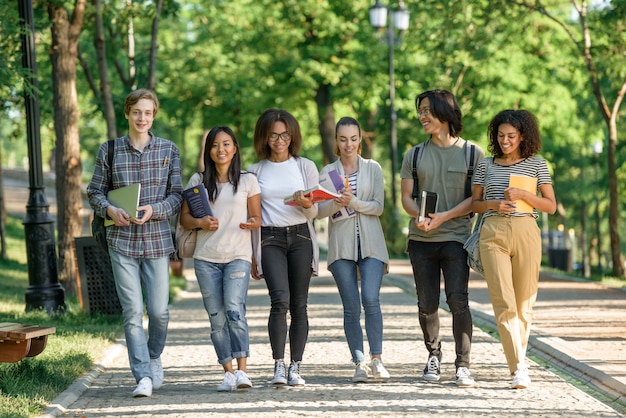 Young happy students walking while talking. Looking aside.