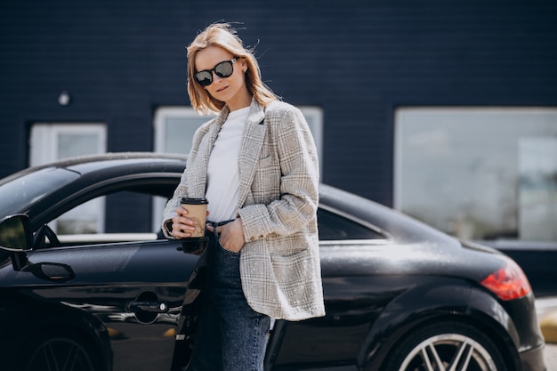 Free photo young happy woman drinking coffee by the car