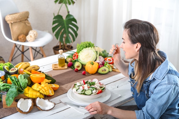 テーブルでサラダを食べる若い、幸せな女