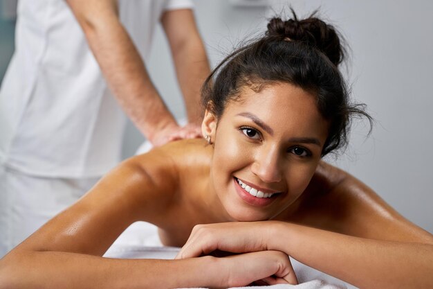 Young happy woman having a back massage while spending a day at beauty spa