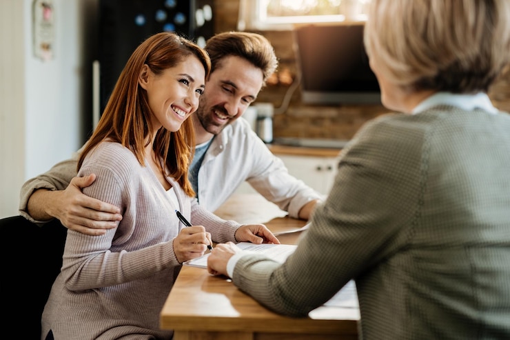 Free Photo young happy woman and her husband signing an agreement with insurance agent during a meeting