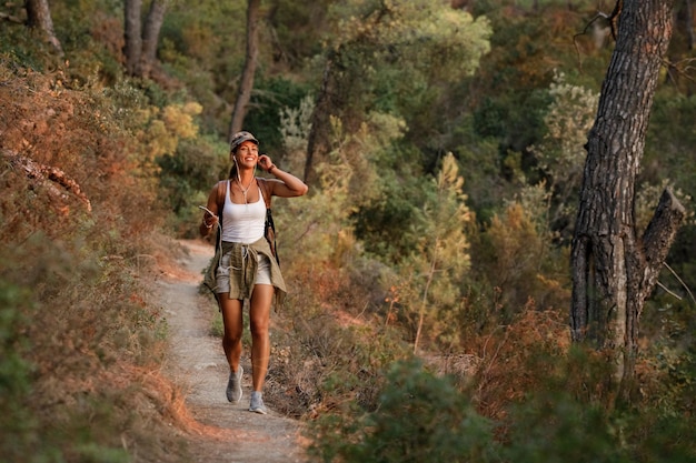 Young happy woman hiking in the mountains while using her mobile phone