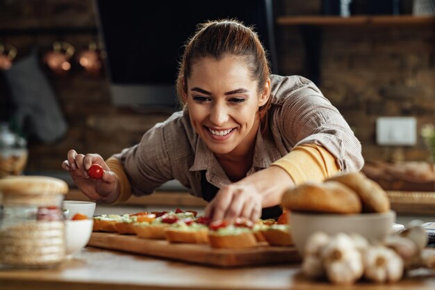 Young happy woman preparing healthy food while making bruschetta in the kitchen