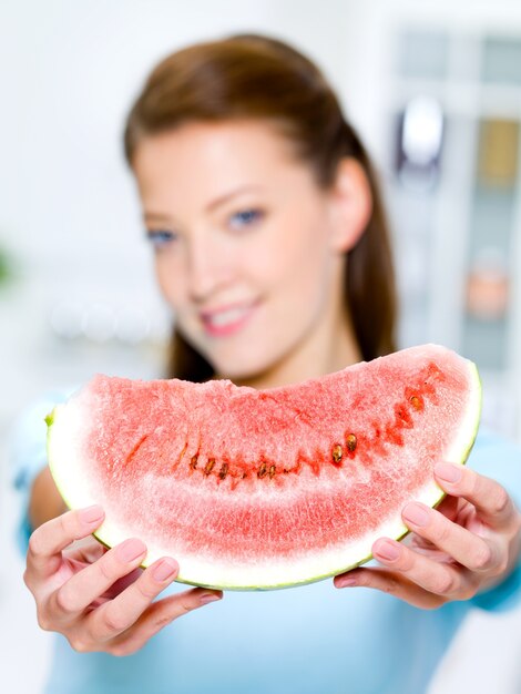 Young happy woman shows a red water-melon
