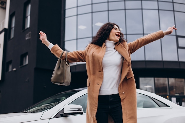 車のそばに立っている若い幸せな女