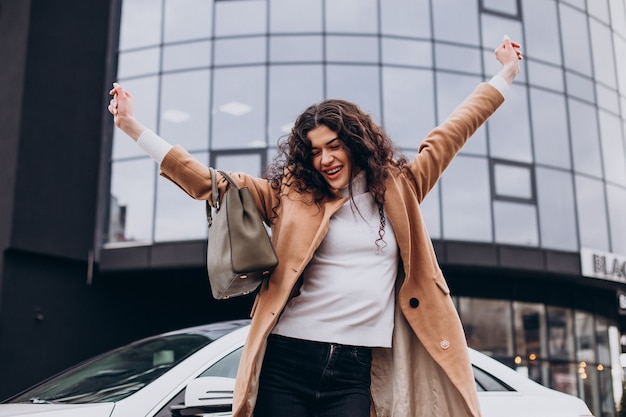 車のそばに立っている若い幸せな女