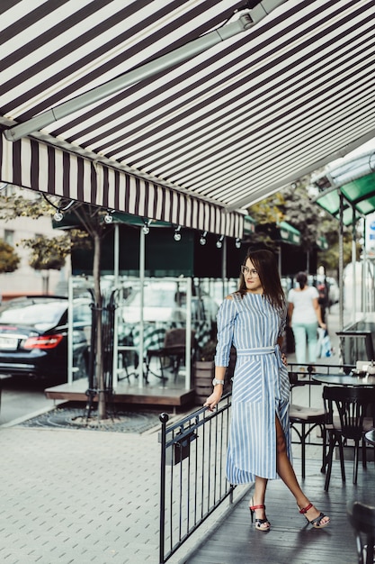 young happy woman in a street cafe smiling laughs drinking coffee on a terrace