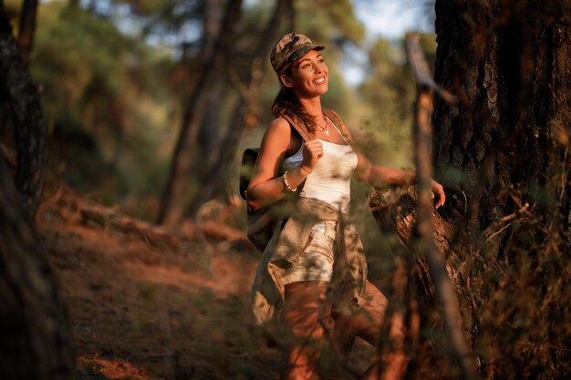 夕焼けの自然の中でハイキングしながら休憩と景色を見ている若い幸せな女性