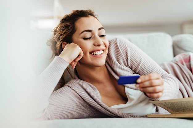 Young happy woman waiting for pregnancy test outcome while relaxing at home