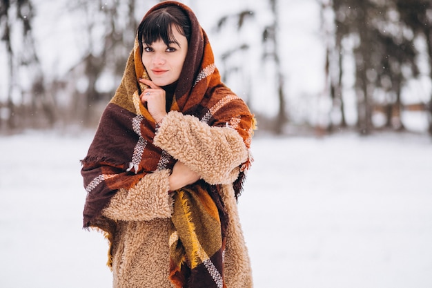 Giovane donna felice in panni caldi in un parco d'inverno