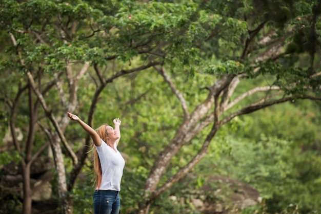 Foto gratuita la giovane donna felice con lo zaino che solleva la mano gode di con la natura.