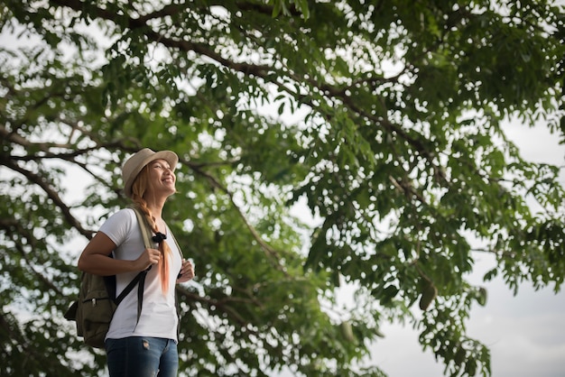 Young happy woman with backpack standing looking to the river. 