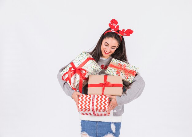 Young happy woman with deer antlers headband and present boxes