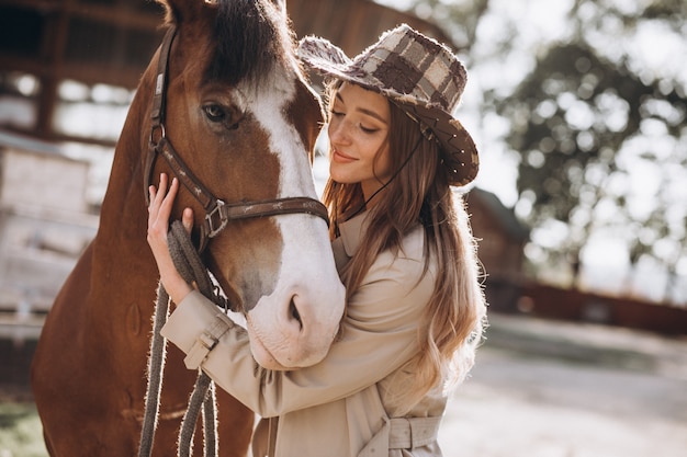 牧場で馬を持つ若い幸せな女