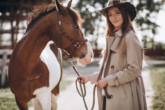牧場で馬を持つ若い幸せな女