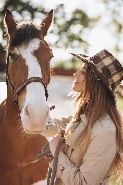 牧場で馬を持つ若い幸せな女