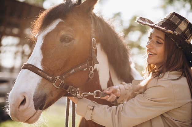 牧場で馬を持つ若い幸せな女