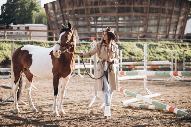 牧場で馬を持つ若い幸せな女