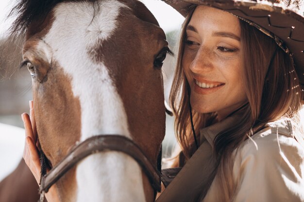 牧場で馬を持つ若い幸せな女