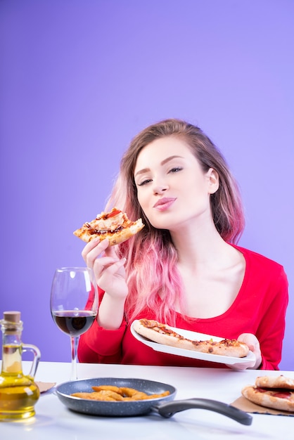 Free photo young happy woman with pink hair enjoying her slice of pizza