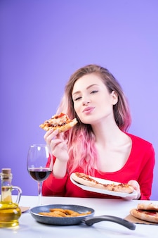 Young happy woman with pink hair enjoying her slice of pizza