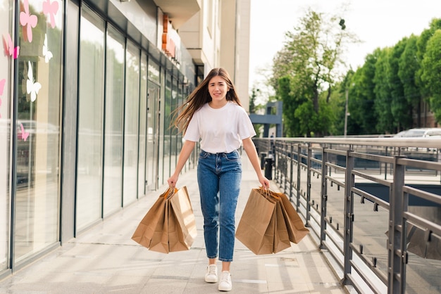 Young happy woman with shopping bags walking on street.