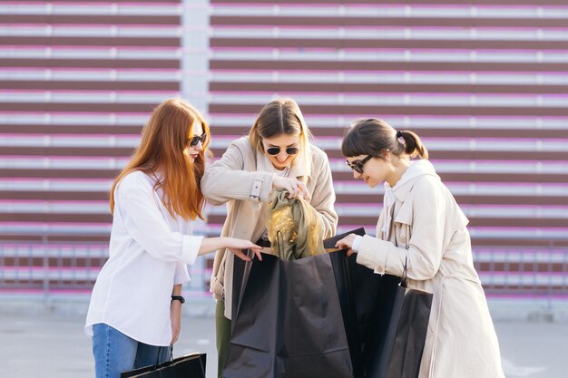 Young happy women with shopping bags walking on street.