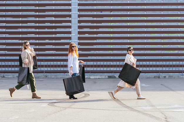 Young happy women with shopping bags walking on street.