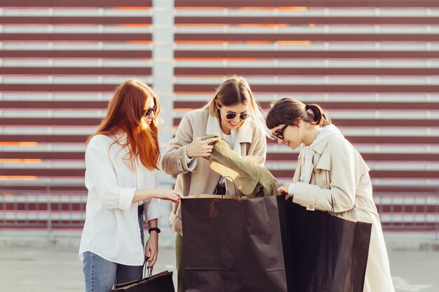 Young happy women with shopping bags walking on street.