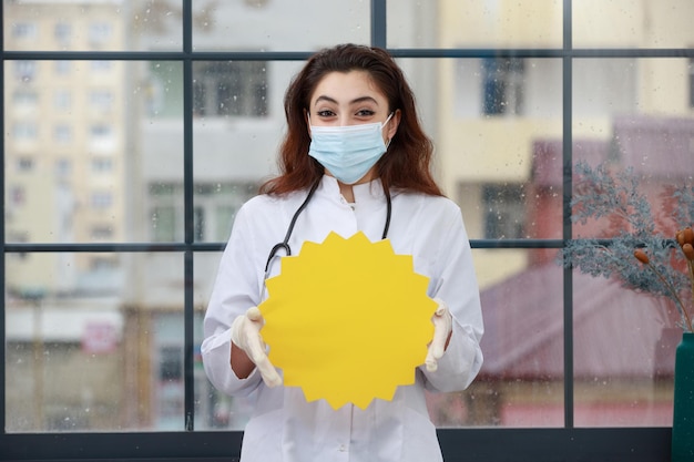 Foto gratuita giovane operatore sanitario in maschera che tiene la bolla dell'idea e sorridente