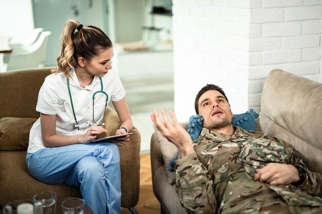 Young healthcare worker listening to military man who is lying down on sofa and talking to her