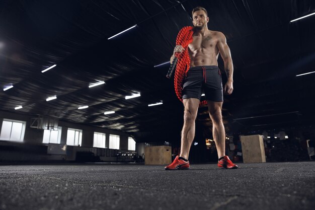 Young healthy male athlete doing exercises in the gym