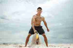 Free photo young healthy man athlete doing squats at the beach