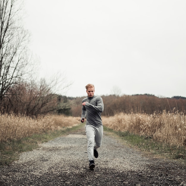 Young healthy man running on the dirt road