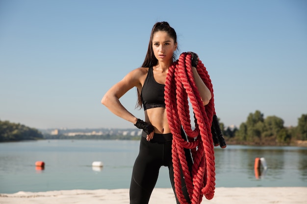 Young healthy woman posing with the ropes at the beach.