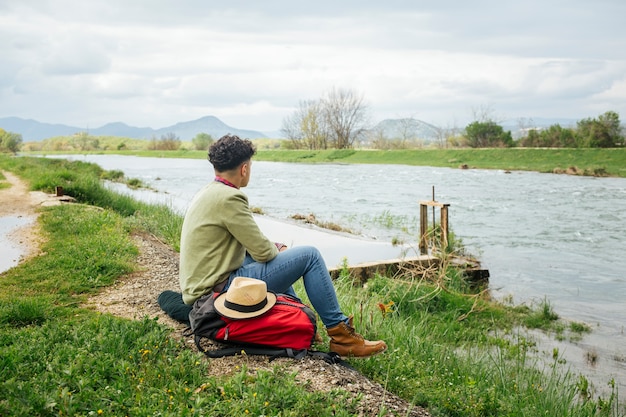 Young hiker siting near beautiful river