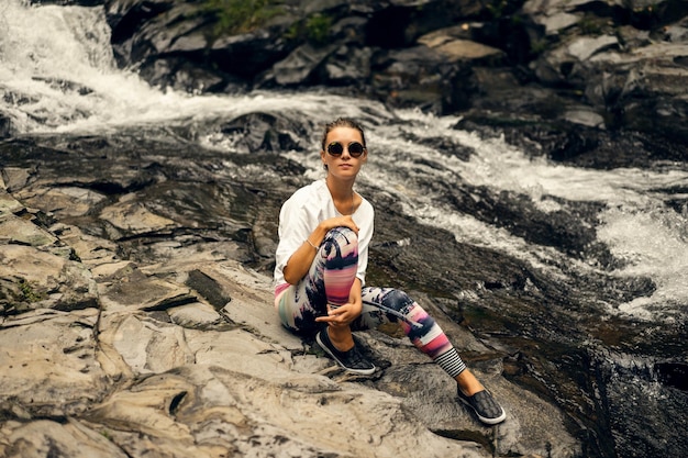 young hippie woman in bright leggings and round glasses in nature