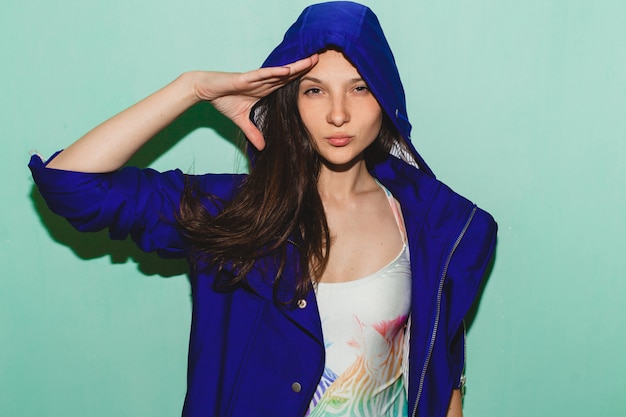 Young hipster beautiful woman, blue  posing against blue wall, swimsuit fashion trend summer, cool face expression