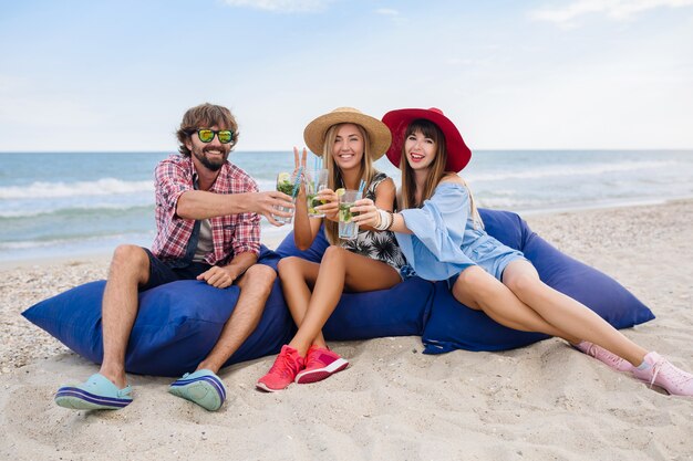 Молодая хипстерская компания друзей на отдыхе в пляжном кафе, пьет коктейль мохито