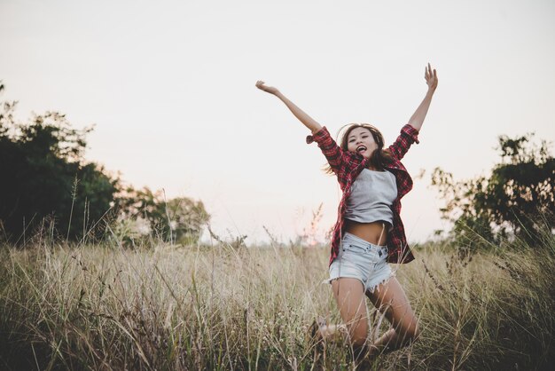 Young hipster girl having fun jumping in the summer field.