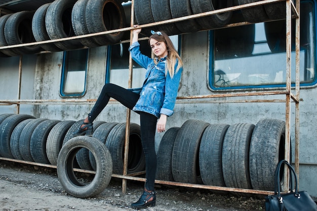 Young hipster girl in jeans jacket and head scarf at tire fitting zone