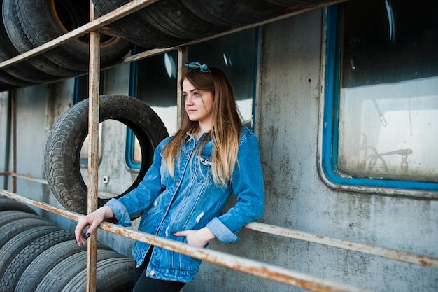 Young hipster girl in jeans jacket and head scarf at tire fitting zone