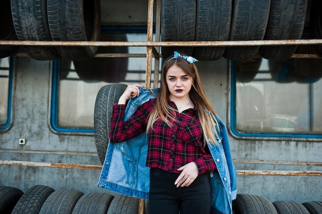 Free photo young hipster girl in jeans jacket and head scarf at tire fitting zone